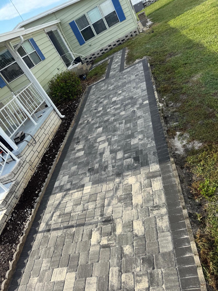 Paver walkway with a charcoal border beside the house