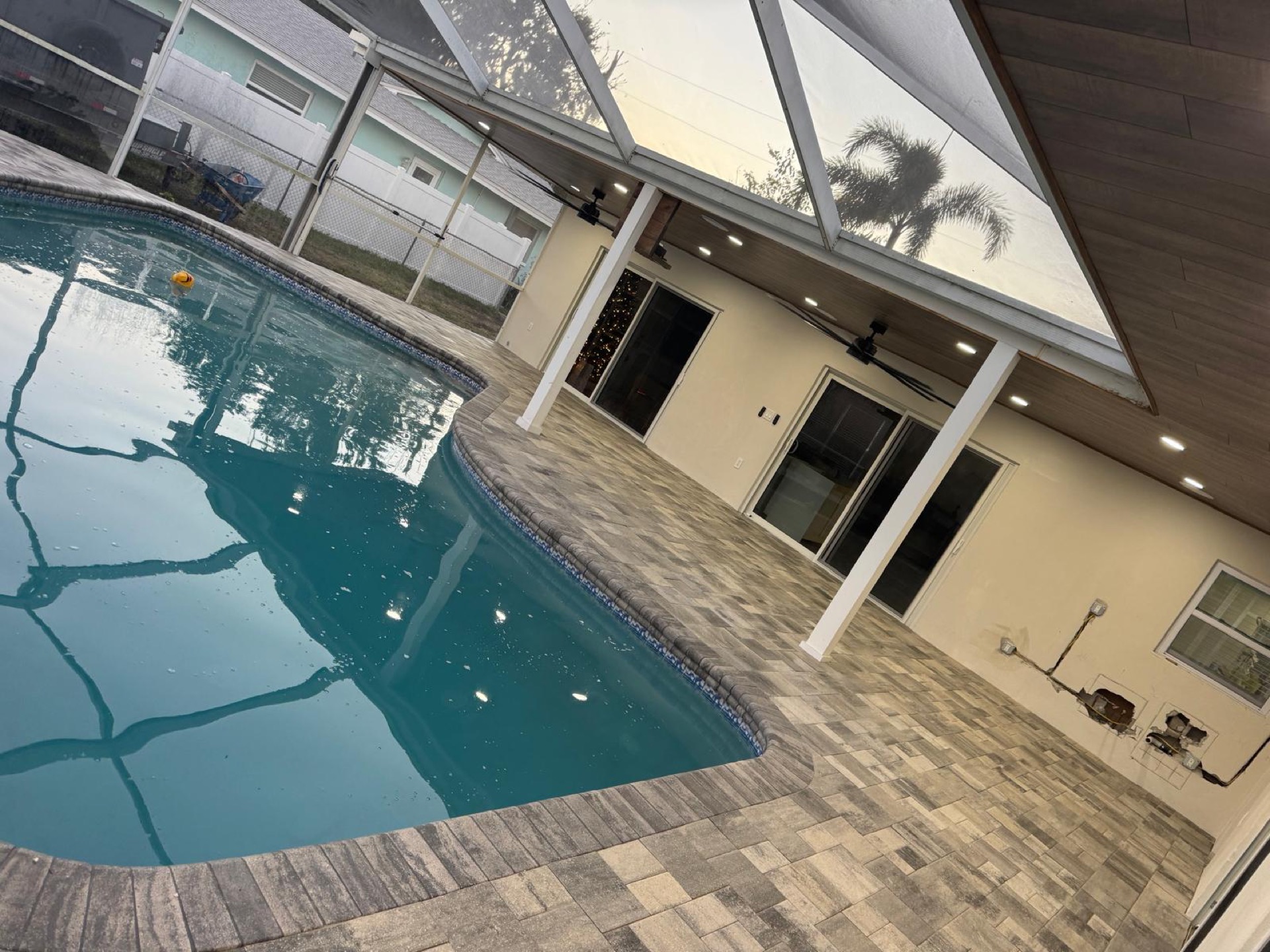 Pool deck in charcoal-blend pavers with a white pavilion, installed by PaveWorks in Largo, Florida